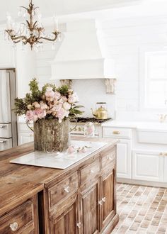 a kitchen with white cabinets and pink flowers on the island