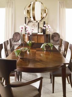 a dining room table with chairs and vases on it in front of a mirror