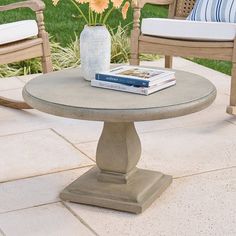 two chairs and a table with flowers in a vase on the ground next to each other