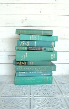 a stack of books sitting on top of a white tile floor next to a wall