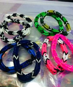 four different colored bracelets sitting on top of a plastic bag with white and black braiding