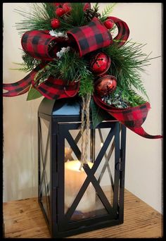 a lantern with christmas decorations on top and a candle in the middle, sitting on a table