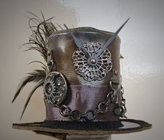 IMPORTANT NEWS!!  Due to the UK leaving the EU, postage prices have increased but have kept them as low as I can for my customers. If you would like to purchase more than one item, please contact me first so I can invoice you with the lowest postage price. Unique, leather mini top hat. Steampunk style. Attaches to the head by 2 alligator clips Approx Size: Brim Width 15.5cm                         Height 10cm Bespoke mini top hats available. One of a kind Details: Leather top hat Metal details Metal buckle Ribbon band Clock parts Metal chain Black feathers Peacock feather Metal spike Tracked and signed postage worldwide available, please contact me before purchasing. Handmade Fitted High Crown Mini Hats, Handmade Fitted Mini Hat With High Crown, Handmade Vintage High Crown Top Hat, Steampunk High Crown Top Hat For Cosplay, Steampunk Top Hat With High Crown For Themed Events, Steampunk High Crown Mini Hat For Themed Events, Vintage Top Hat With High Crown For Cosplay, Vintage Handmade Costume Hats And Headpieces For Gifting, Vintage High Crown Top Hat For Cosplay