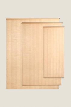 three beige blinds with vertical blinders on top of each one in front of a white wall