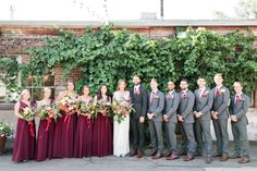 a group of people standing next to each other in front of a wall with ivy growing on it