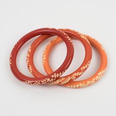 This lovely Galalith bracelet bangle set of three pieces features a chunky spacer domed shape with deep floral carving, all around. A trio of orange variations with peach pink, ginger orange, and orange-red spice colors over a white background.  Measurements for one bracelet: Inside across is 2.44 in diameter (6.2 cm) - outside across is 3.13 in diameter (7.9 cm) - width is 0.32 in (0.8 cm) - width for the three bracelets together is 0.94 in (2.4 cm). The inner circumference of the bracelets is Traditional Orange Bangle Bracelets, Orange Festival Bangle Jewelry, Traditional Orange Bangle Bracelet, Orange Bangles, Orange Bohemian Bangle Jewelry, Unique Orange Bangle Jewelry, Handmade Orange Round Bangle, Red Spice, Pink Ginger