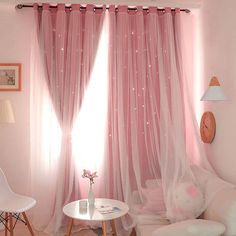 a living room with white furniture and pink curtains on the windowsill, along with a small round table