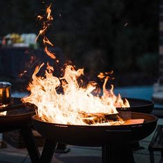 a fire pit sitting on top of a wooden table next to a glass vase filled with liquid