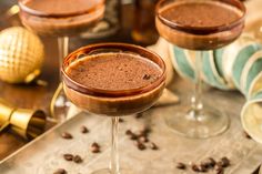 two glasses filled with chocolate drink sitting on top of a table