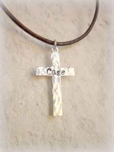 "This personalized cross necklace is perfect for that young man celebrating his First Holy Communion, Confirmation or any religious celebration or just because. This hand hammered cross necklace comes with a boy's/man's name on the front and choice of date stamped onto the back of a silver stainless steel cross. The cross measures 1\" x 5/8\". Choose from 14\"- 24\" length leather cord. Choose from black, distress brown, sun tan brown or turquoise leather cord. This necklace has a silver lobster Personalized Silver Cross Pendant Necklace, Personalized Crucifix Cross Necklace, Father's Day Gift Cross Necklace, Personalized Cross Necklace For Father's Day, Necklace Boys, Cross Necklace Mens, Confirmation Necklace, Boys First Communion, Personalized Cross Necklace