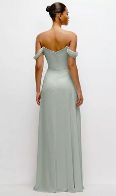 the back of a woman in a light green dress with her hands on her hips