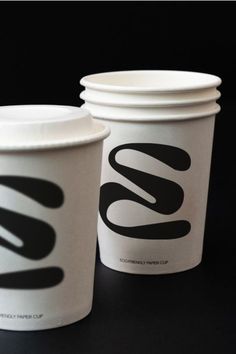 two coffee cups sitting side by side on top of a black table with the word go written on them