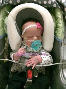 a baby in a car seat wearing a pacifier