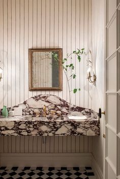 a bathroom with marble counter tops and black and white checkered flooring on the walls