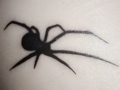 a black spider tattoo on the back of a woman's shoulder