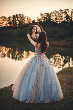 a woman in a blue dress holding a mirror