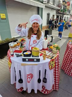 a woman wearing a chef's outfit standing in front of a table with food on it