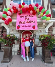 two women standing in front of a building with balloons on the door and a sign that says we picked the best batch