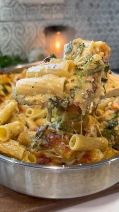 a pasta dish with broccoli and cheese being lifted from the pan by a spatula