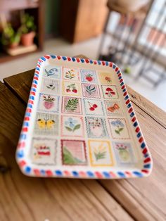 a plate with stamps on it sitting on top of a wooden table next to a potted plant