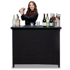 a woman standing behind a bar filled with bottles and glasses