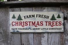 a farm fresh christmas trees sign on a wooden fence