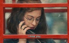 a woman talking on a cell phone with the words i miss you in front of her