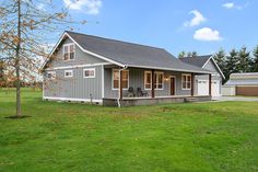 a gray house sitting on top of a lush green field