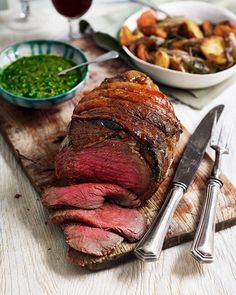 a large piece of meat sitting on top of a cutting board next to some vegetables