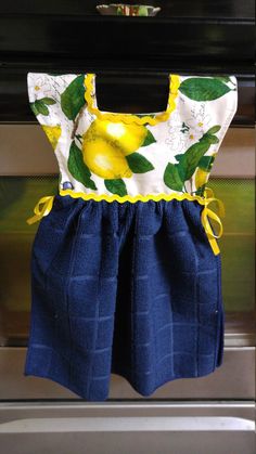 a blue dress with lemons on it is hanging from a rack in front of an oven