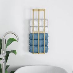 a white bath tub sitting next to a green plant in a bathroom under a towel rack