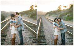 a man and woman kissing on train tracks with the sun setting in the back ground