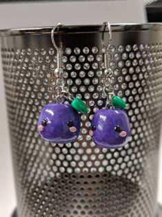 two purple fruit shaped earrings with green leaves on them