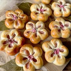 small pastries are arranged on a cutting board with leaves and flowers in the middle