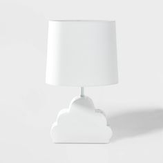 a white table lamp with a cloud shaped shade on it's base, against a white background