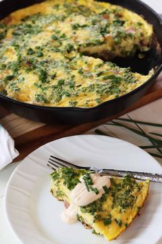 an omelet on a plate with a fork next to it and a skillet in the background