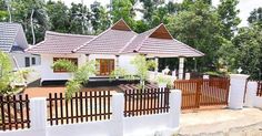 a white house with wooden fence and trees in the background