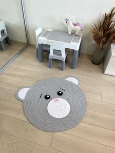 a rug with a bear face on the floor next to a toy horse and table