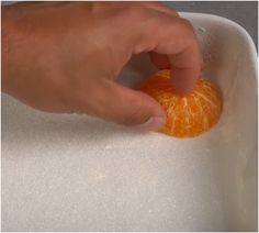 a person is peeling an orange in a bowl