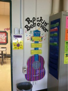 the door to an office is decorated with music notes and guitar magnets, along with a trash can