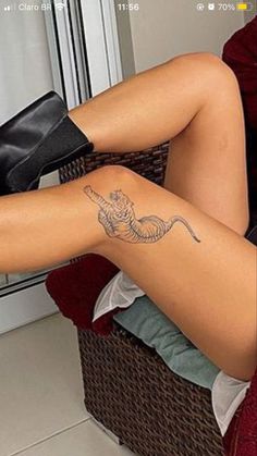 a woman sitting in a chair with her legs crossed and tattoos on the leg,