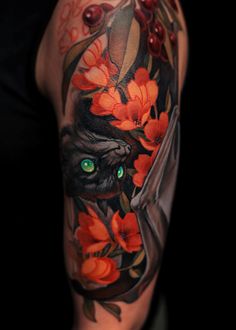 an arm with flowers and a black cat on it's side, showing the green eyes