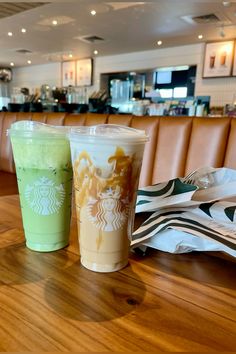 two starbucks drinks sitting on top of a wooden table