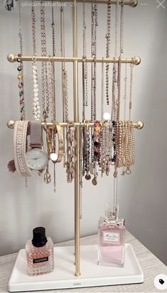 a jewelry rack with many different necklaces and watches on it next to a bottle of perfume