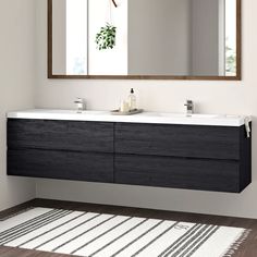 a bathroom with two sinks and a large mirror on the wall next to a rug