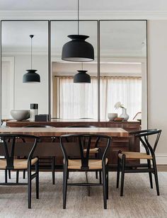 a dining room table with four chairs and a large mirror in the backround