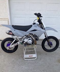 a motorcycle parked in front of a garage door with a ladder attached to the bike