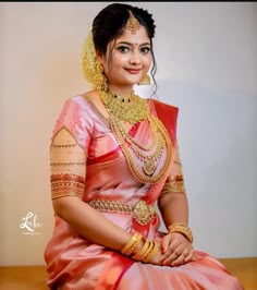 a woman in a pink saree sitting on a table