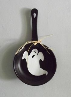 a black and white ceramic spoon with a ghost painted on it's side hanging from a string