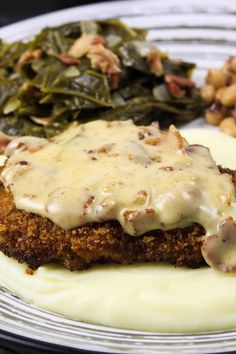 a plate topped with meat covered in gravy next to beans